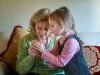 Grandmother teaching granddaughter to sew indoors.