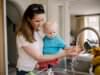 Mother and toddler washing hands at kitchen sink.