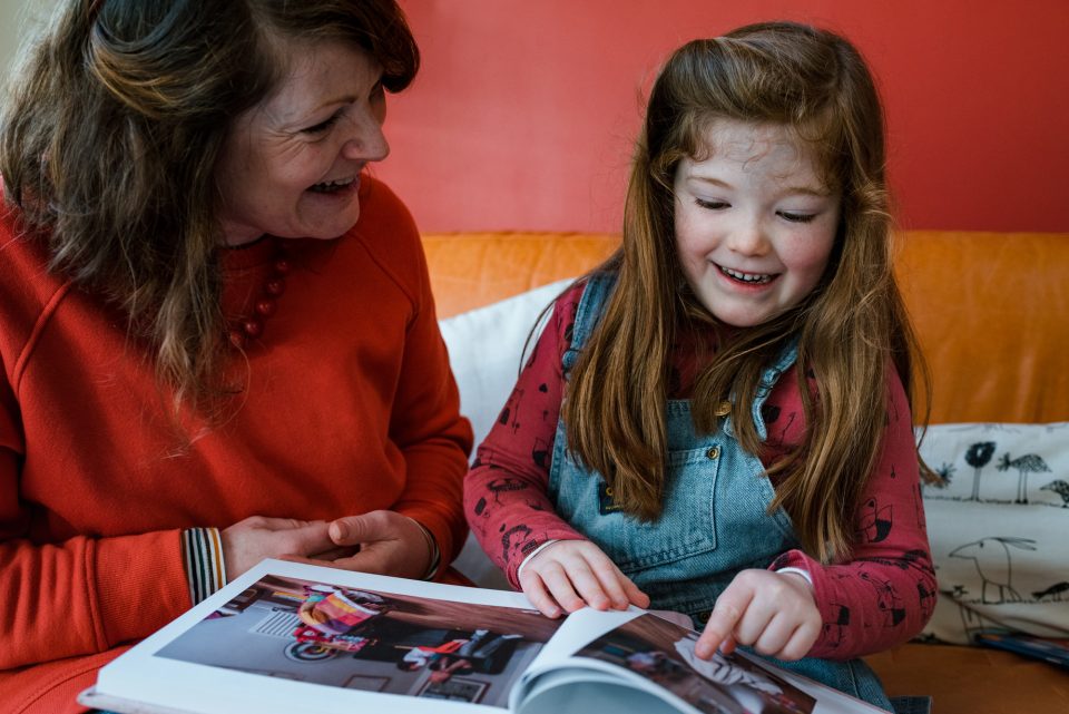 Woman and child reading book together smiling.