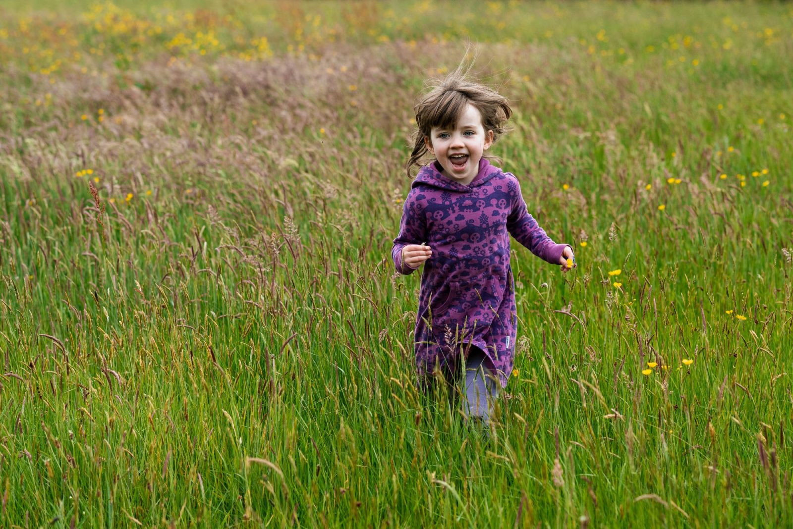 Child running joyfully through a flower meadow.