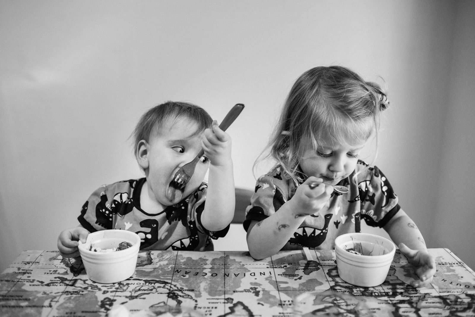 Toddlers enjoying mealtime together, black and white photo.