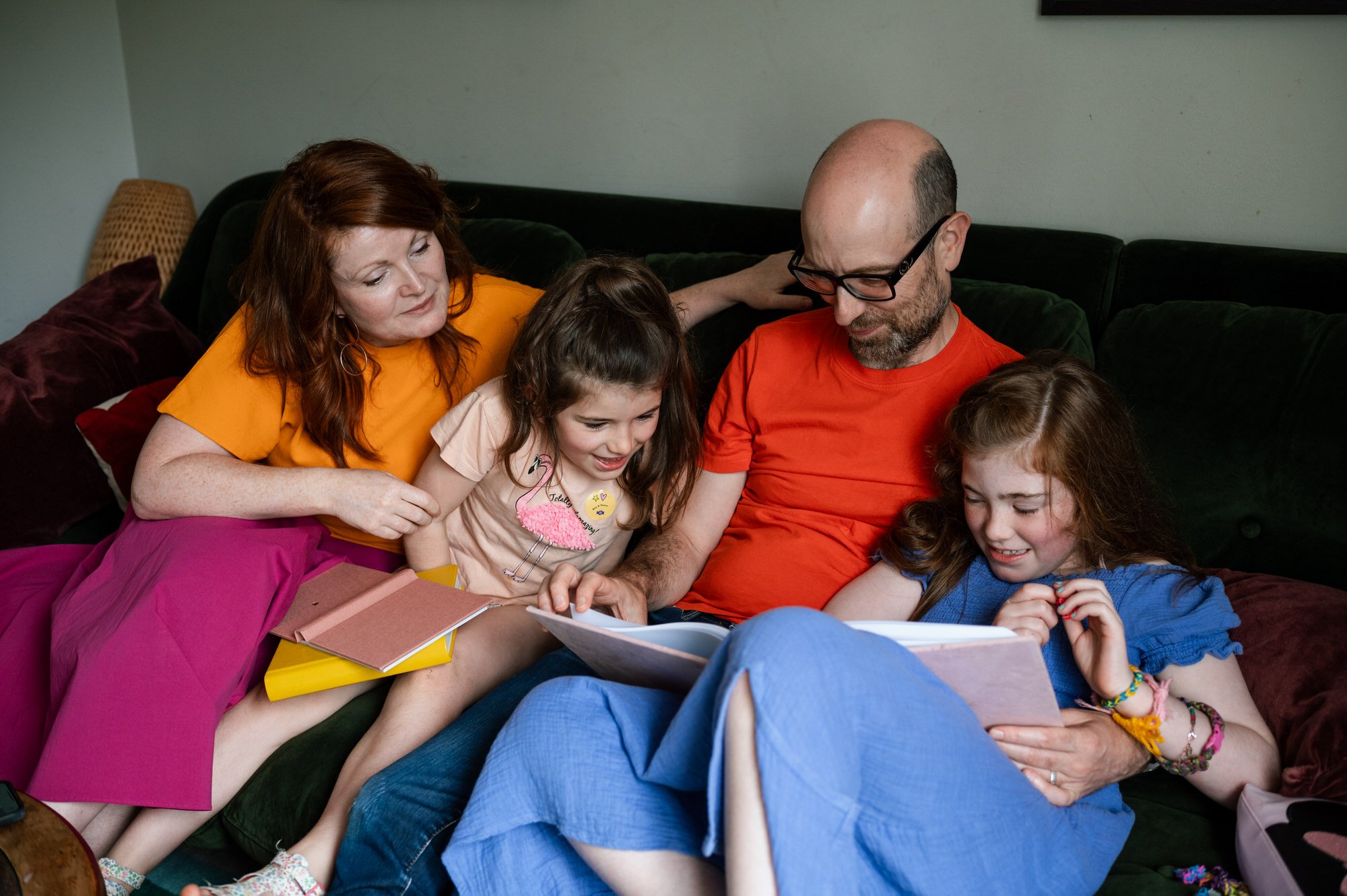 Family reading books together on a sofa.